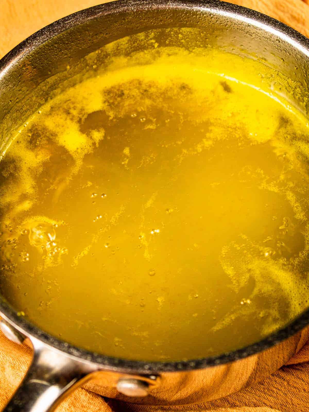 orange simple syrup simmering in a silver pot
