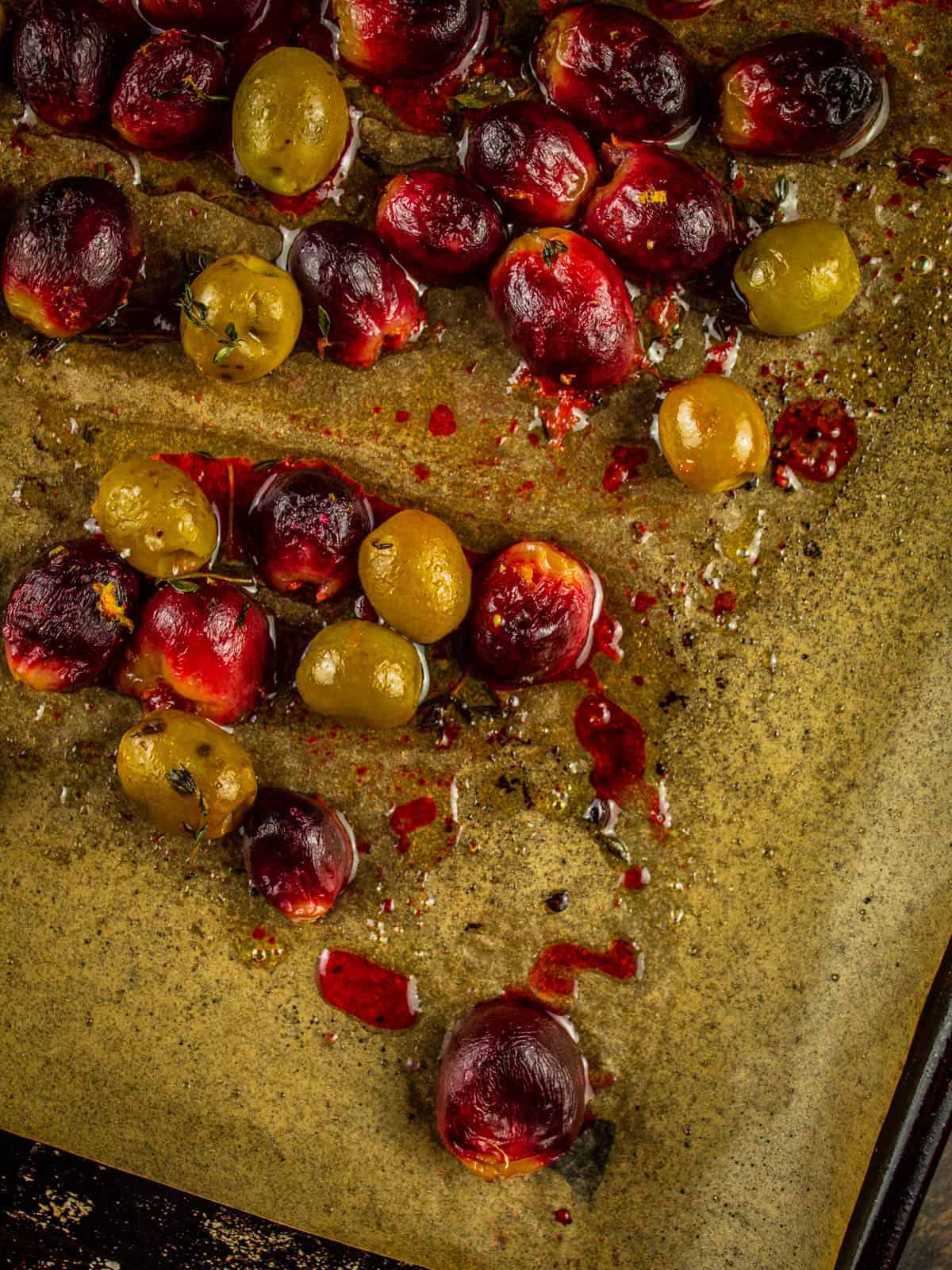 freshly roasted red grapes and green olives on a sheet pan