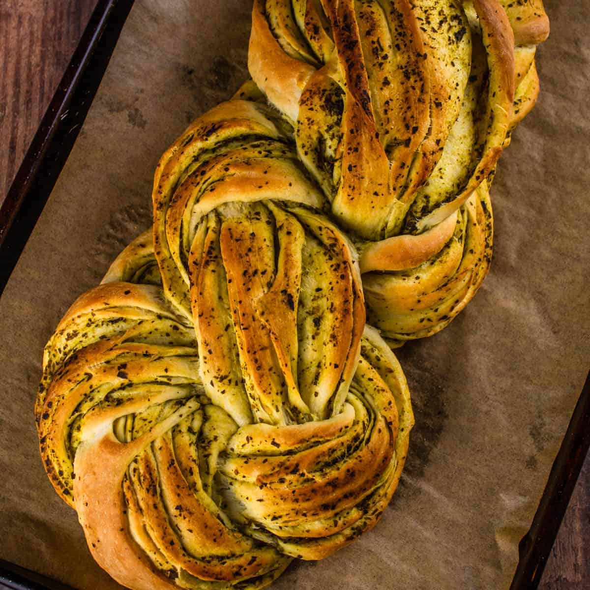 braided loaf of pesto bread on a sheet pan