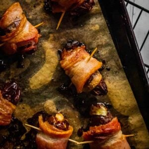bacon wrapped dates stuffed with cheese on a sheet pan