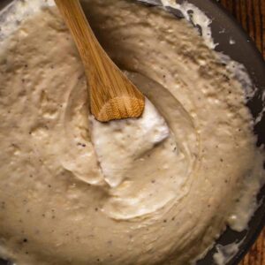 alfredo sauce in a pan with a wooden spoon