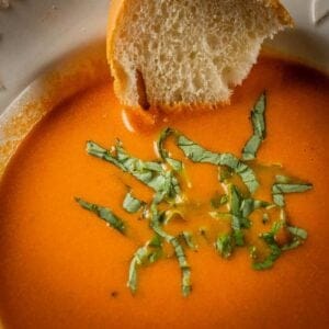 bowl of creamy tomato soup with fresh basil and italian bread