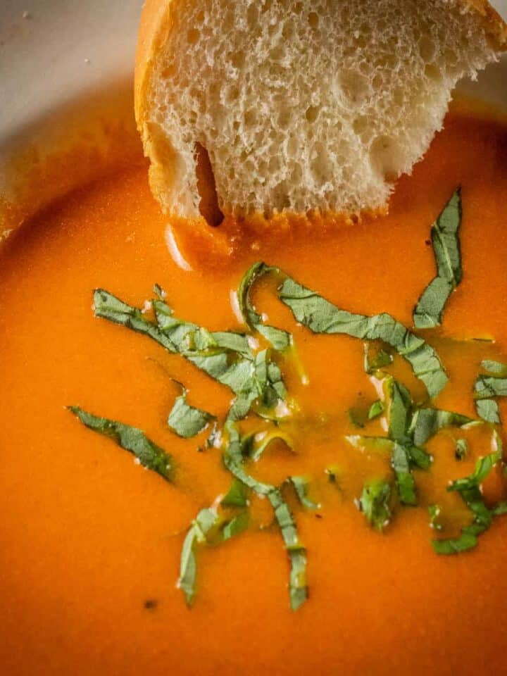 bowl of creamy tomato soup with fresh basil and italian bread