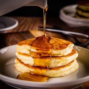 stack of pancakes with syrup pouring over them
