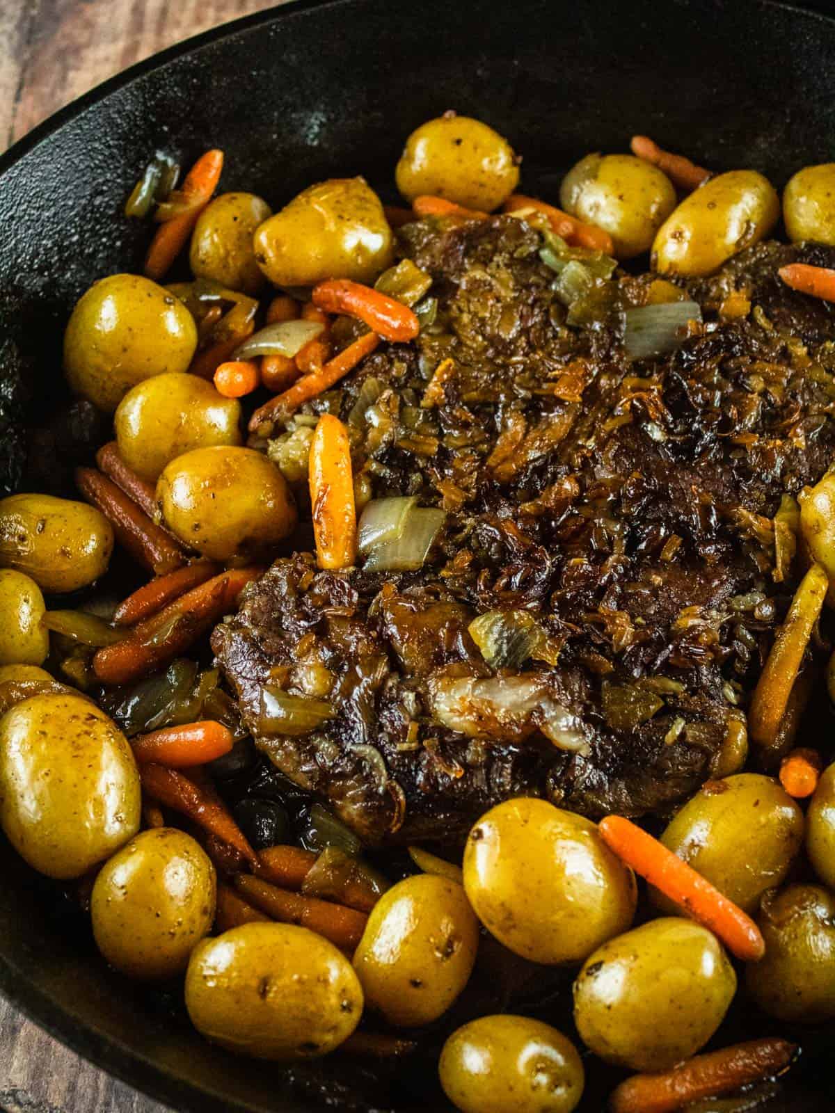 cooked pot roast in a skillet with potatoes and carrots