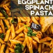 wooden spoon stirring pasta with eggplant, marinara and spinach.