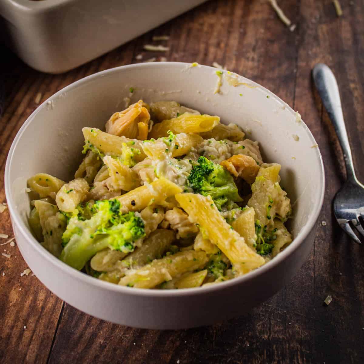 white bowl with penne pasta, broccoli, chicken and alfredo sauce