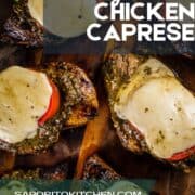 grilled chicken caprese with pesto resting on a wooden cutting board.