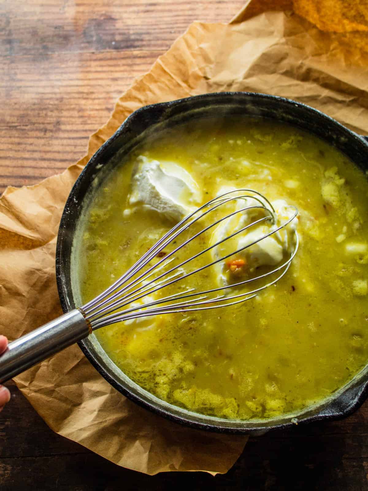 whisk stirring sour cream into a green chili sauce