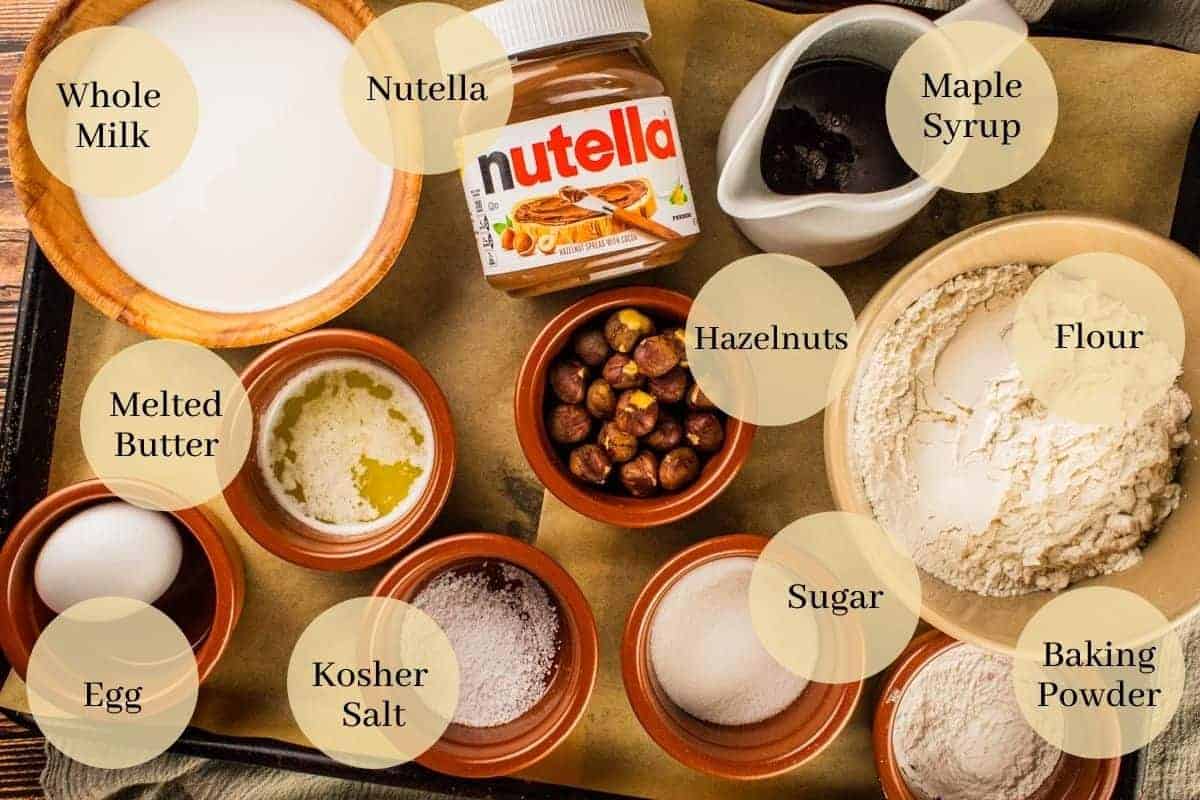 nutella, syrup, hazelnuts, flour, sugar, baking powder, salt, butter, milk and egg on a sheet pan