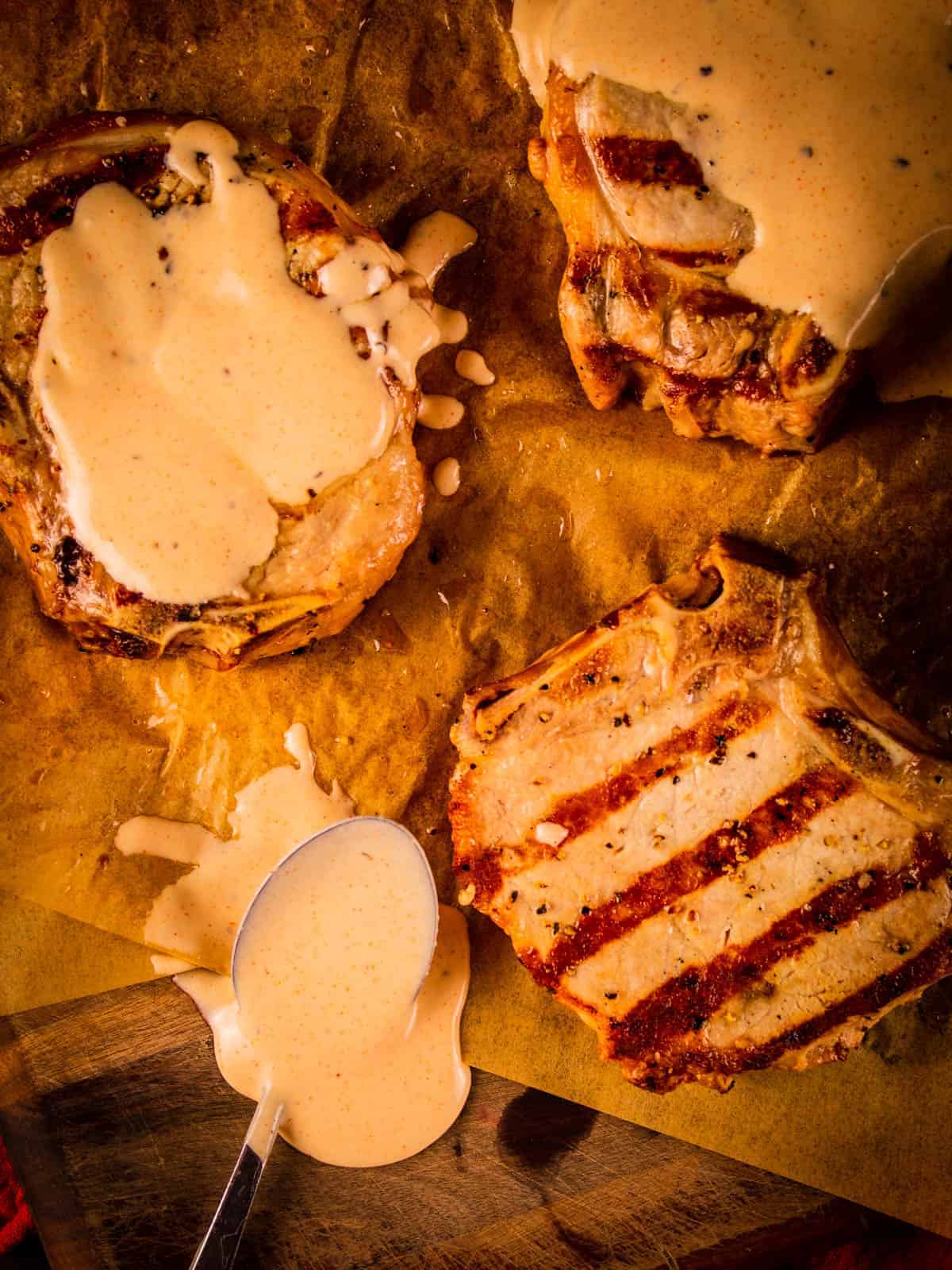 grilled pork chops on a tray covered in white bbq sauce