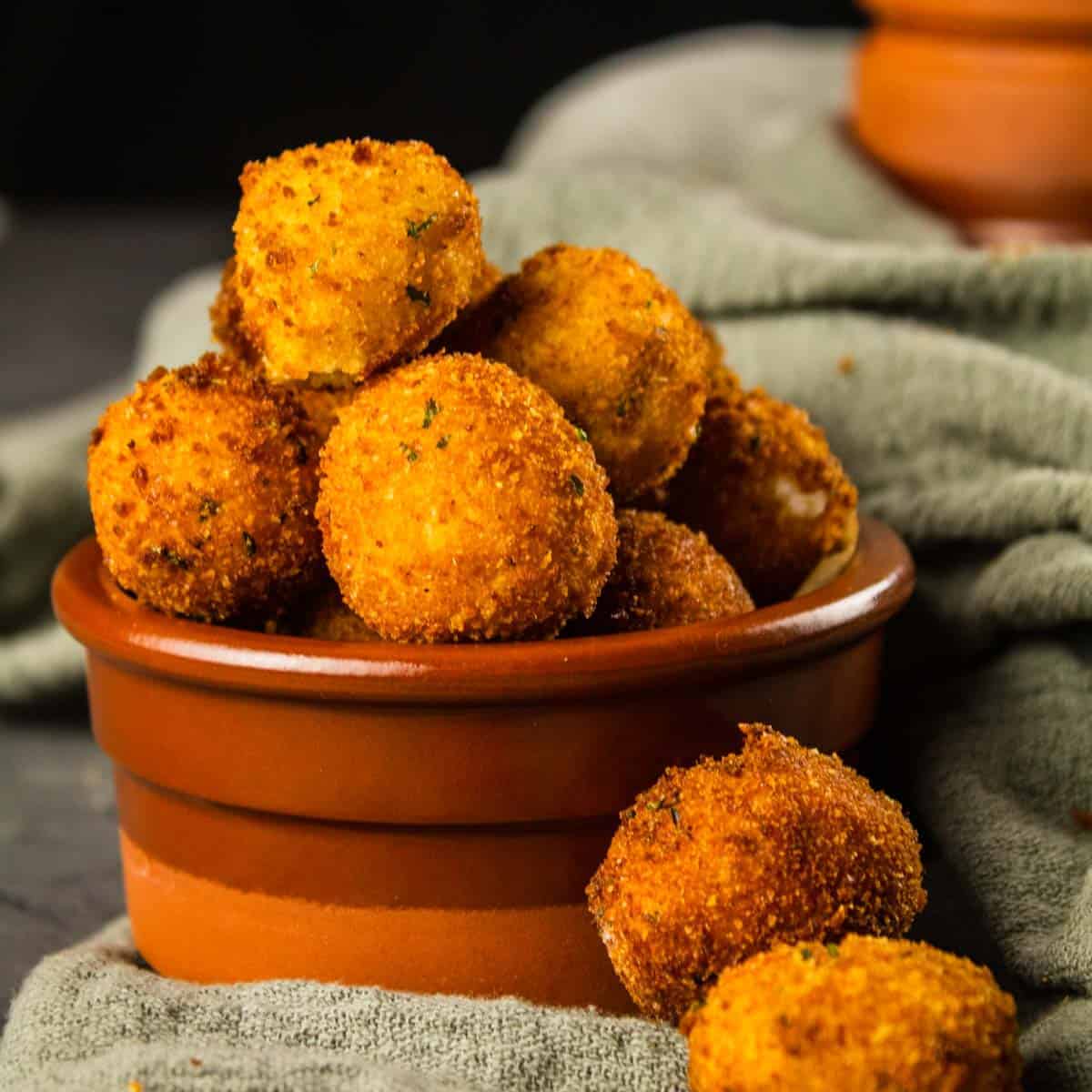 crispy breaded and fried goat cheese balls in a brown cup