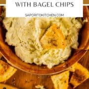 creamy dip in a wooden bowl with bagel chips around it and dipped into it.