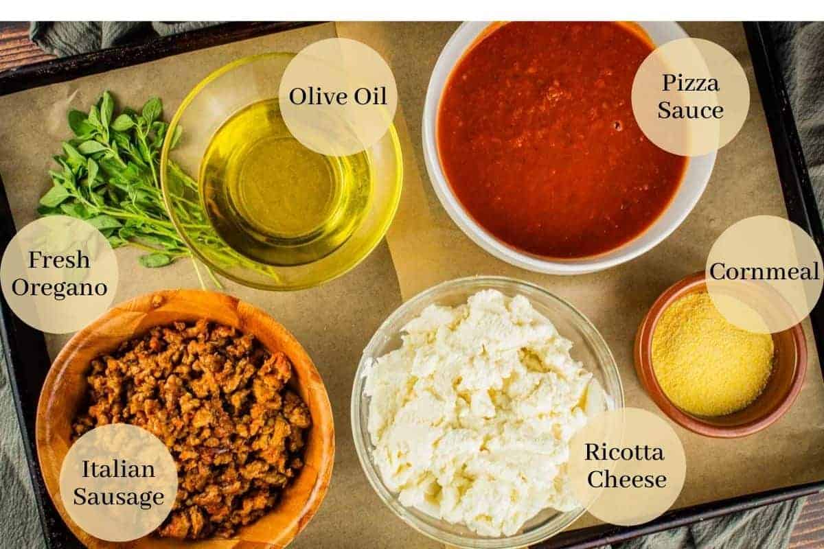 marinara, ricotta, olive oil, cornmeal, sausage and fresh oregano on a sheet pan.