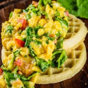 soft scrambled eggs mixed with spinach and tomatoes on waffles
