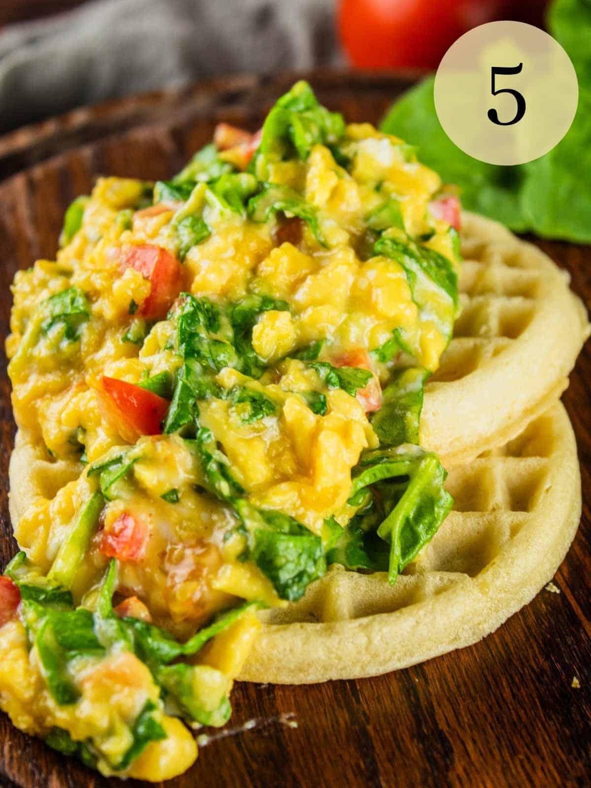 waffles topped with soft scrambled eggs with spinach and tomato mixed in
