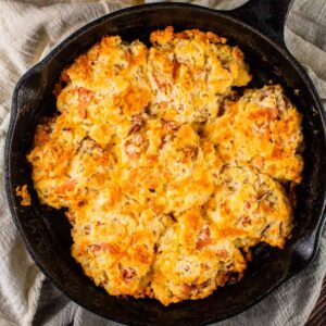 drop biscuits in a cast iron skillet filled with ham and cheese