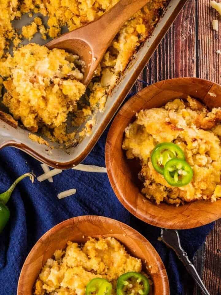baking dish and two wooden bowls filled with cornbread pudding