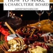 assorted meats, cheeses, crackers and fruit on a tray with wine glasses