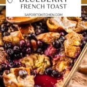 baking dish of overnight french toast with blueberries and wooden spoon