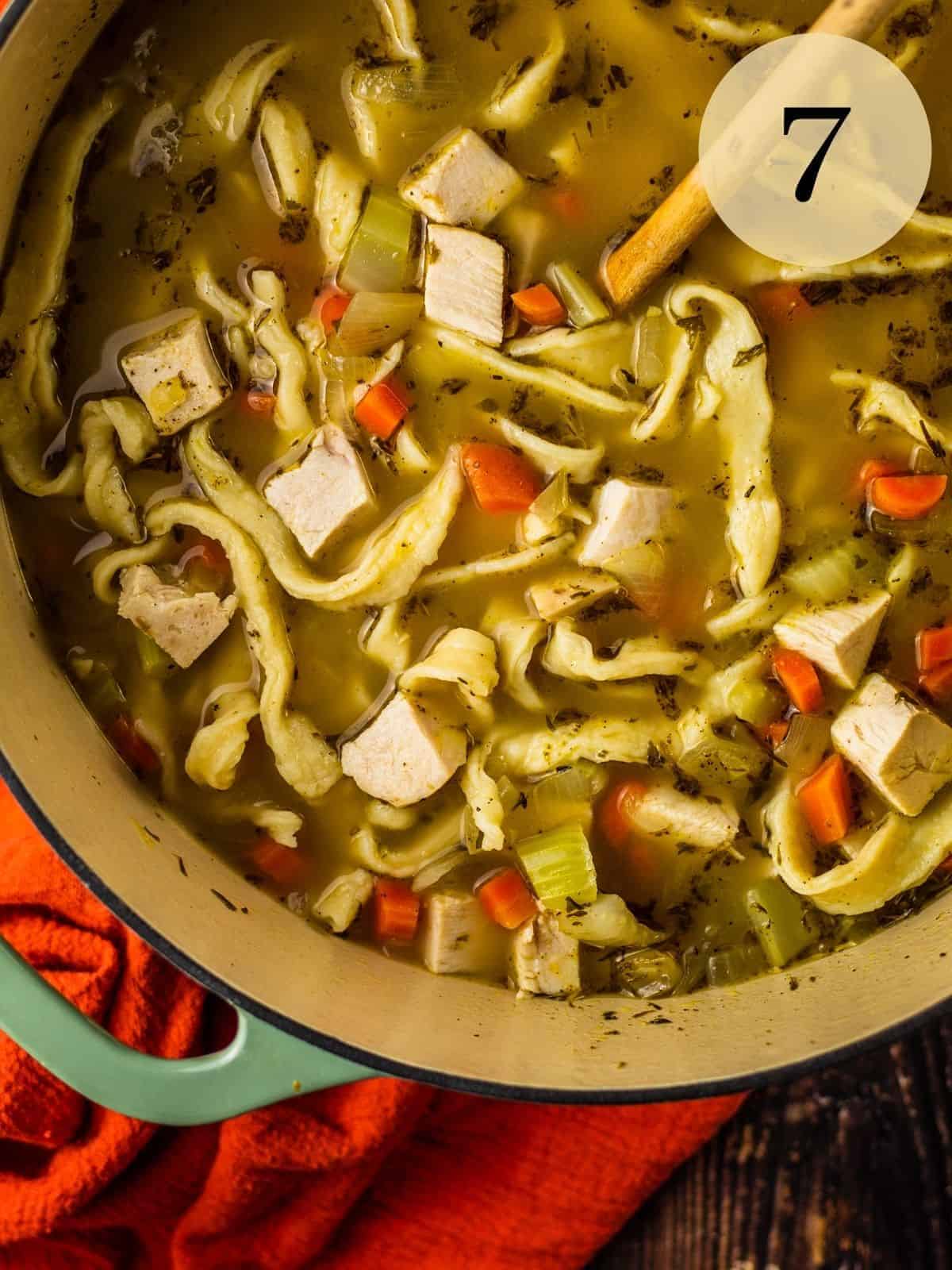 pieces of chicken mixed in with vegetables, noodles and broth in a pot