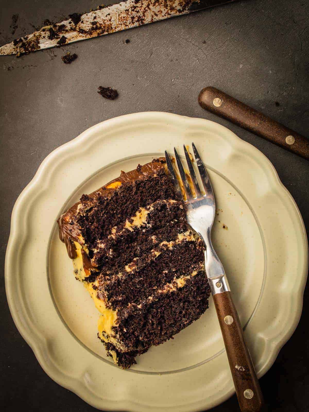 slice of chocolate cake layered with salted caramel buttercream and topped with ganache on plate