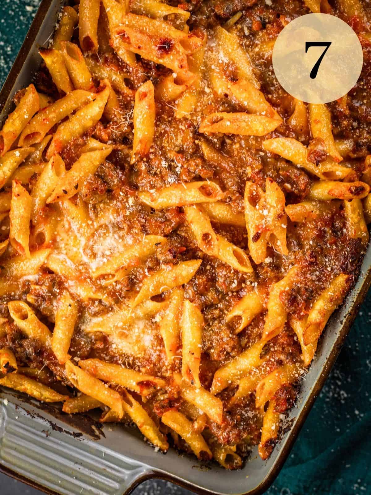 freshly baked mostaccioli pasta with cheese, sauce and italian sausage in a baking dish