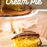 slice of boston cream pie on a plate with a fork next to a cake stand