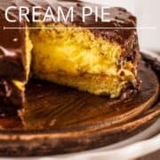 boston cream pie on a cake stand with a slice removed from it