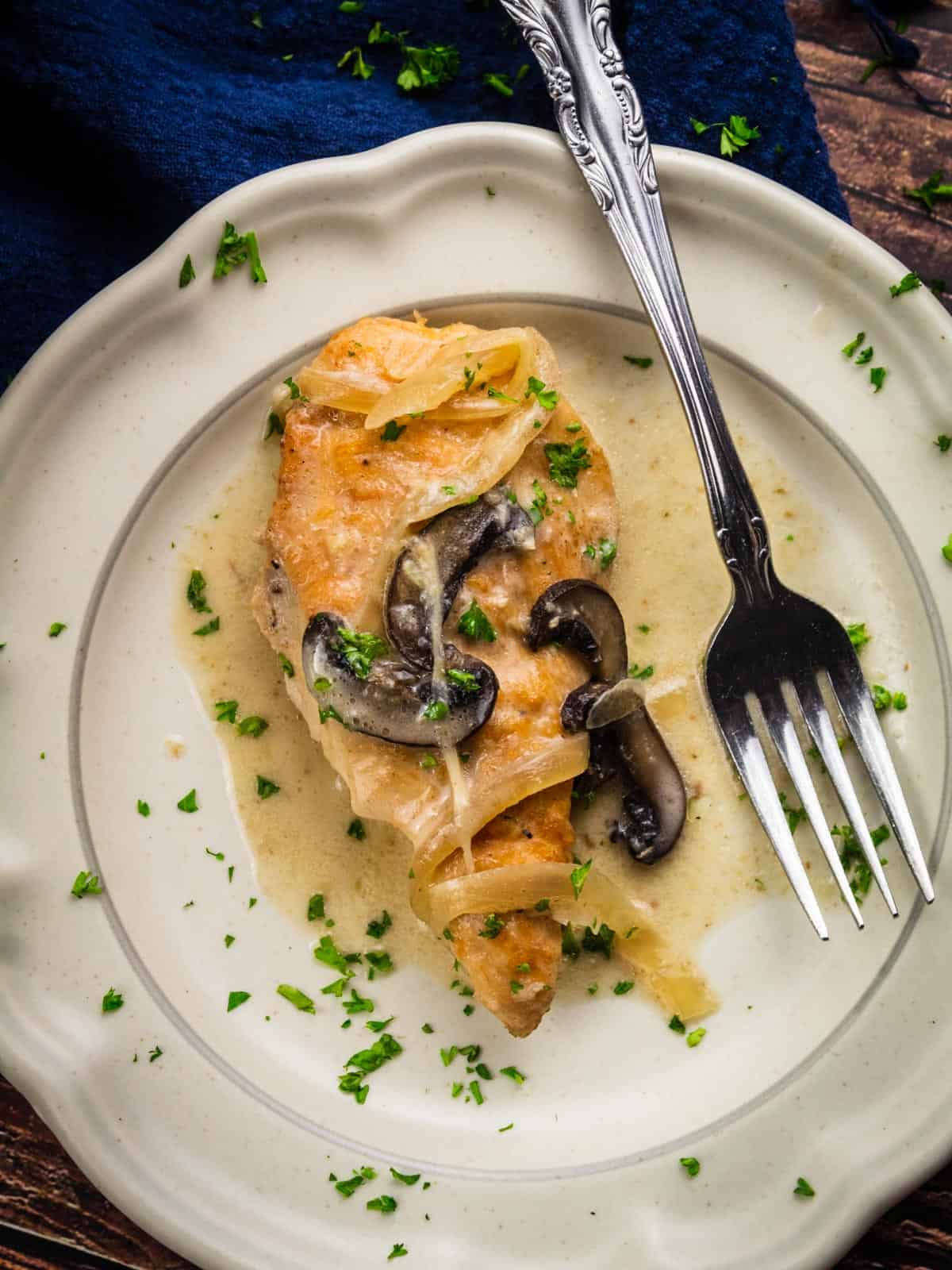 piece of chicken marsala with onions and mushrooms on a plate with a fork