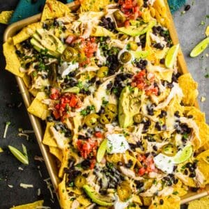 shredded chicken nachos loaded with topping on a sheet pan