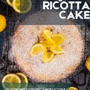 lemon ricotta cake dusted in powdered sugar with lemon wheels on and around.