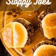sloppy joe sandwiches on a wooden tray with meat spilling out