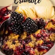 bowl of blackberry crumble with fresh blackberries and ice cream.