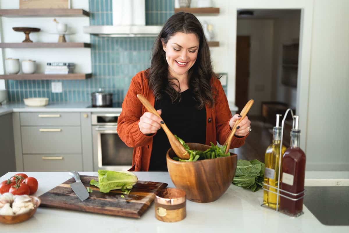 woman tossing a salad in a kitchen.