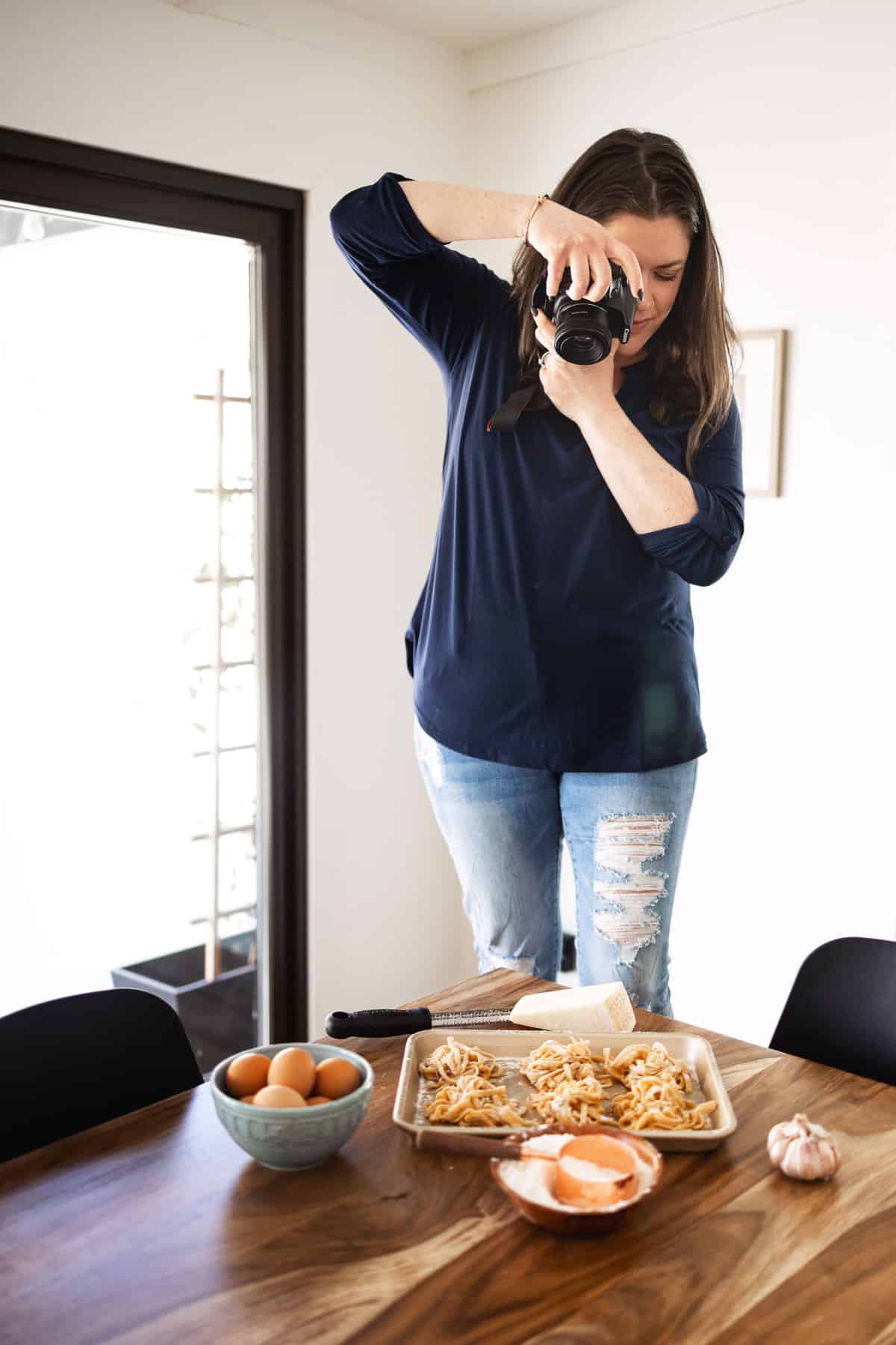 amanda scarlati taking a photo of food on a kitchen table.