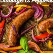 roasted sausages with peppers and onions on a sheet pan with fresh basil.
