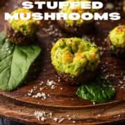 cheese and spinach stuffed mushrooms on a wooden tray with sprinkled cheese.