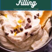 cannoli filling in a bowl topped with grated fresh orange peel and mini chocolate chips.