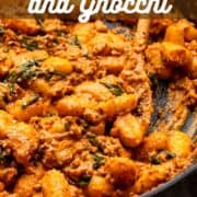 skillet of gnocchi and ground italian sausage with spinach in a creamy tomato sauce.