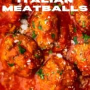 close up shot of meatballs in red sauce, sprinkled with cheese and parsley.