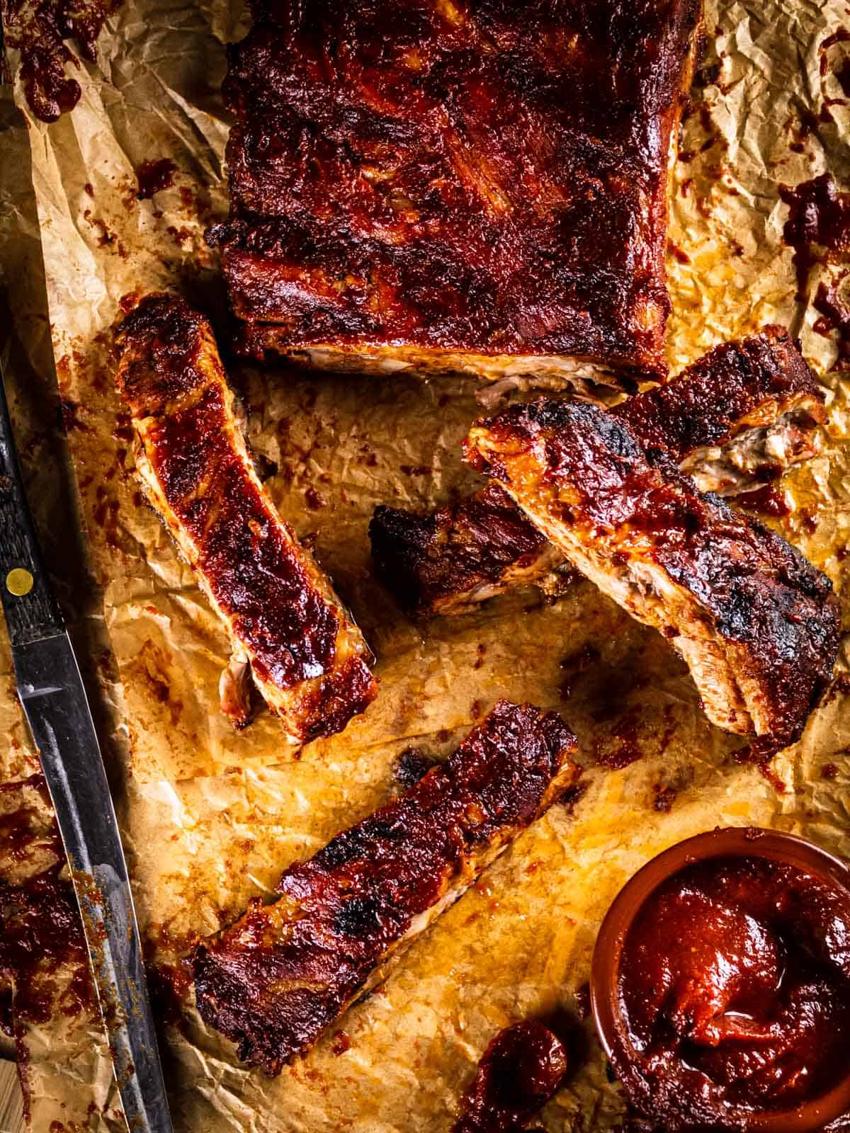 sliced bbq ribs on a table with sauce.
