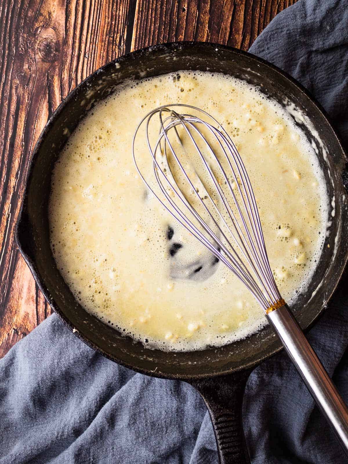 cast iron skillet with a whisk stirring flour, butter and garlic.