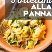 peach colored bowl filled with green and yellow tortellini in a cream sauce with prosciutto.
